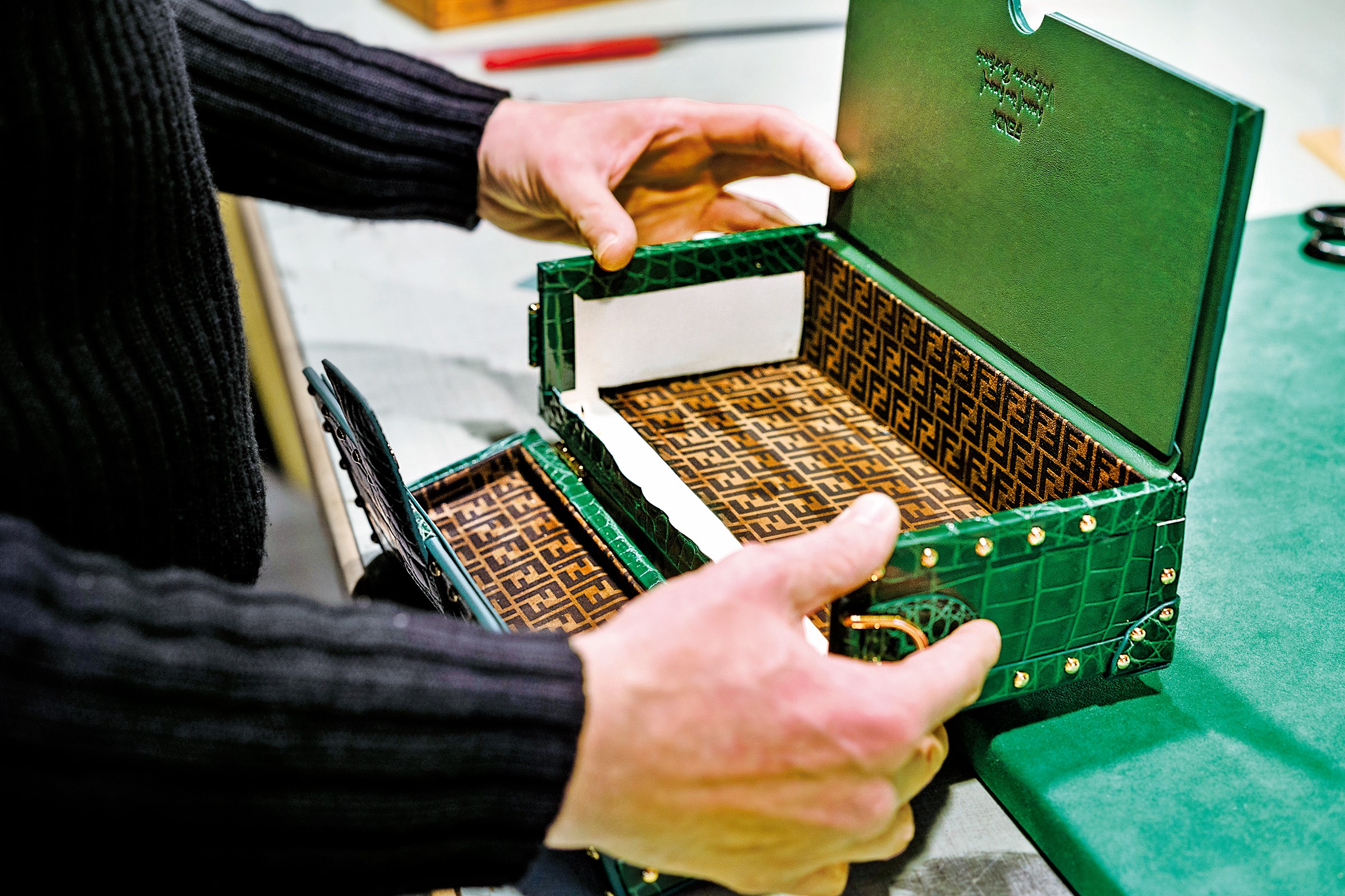 身居現代皮革工藝龍頭的行李箱大師 Bertoni Valigeria，Baguette 包在他手中被改造成微型行李箱，硬挺翡翠綠外殼中以匠心巧設 3 個抽屜，襯墊著柔軟的 FF 麂皮布，兼顧奢華外觀與機能內在。