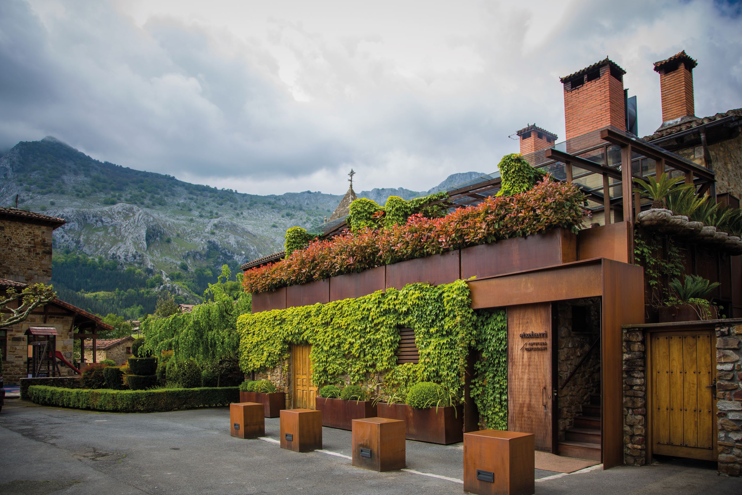 Asador Etxebarri 的其中一侧以布满植栽的外观，回应周遭美丽的自然风光。