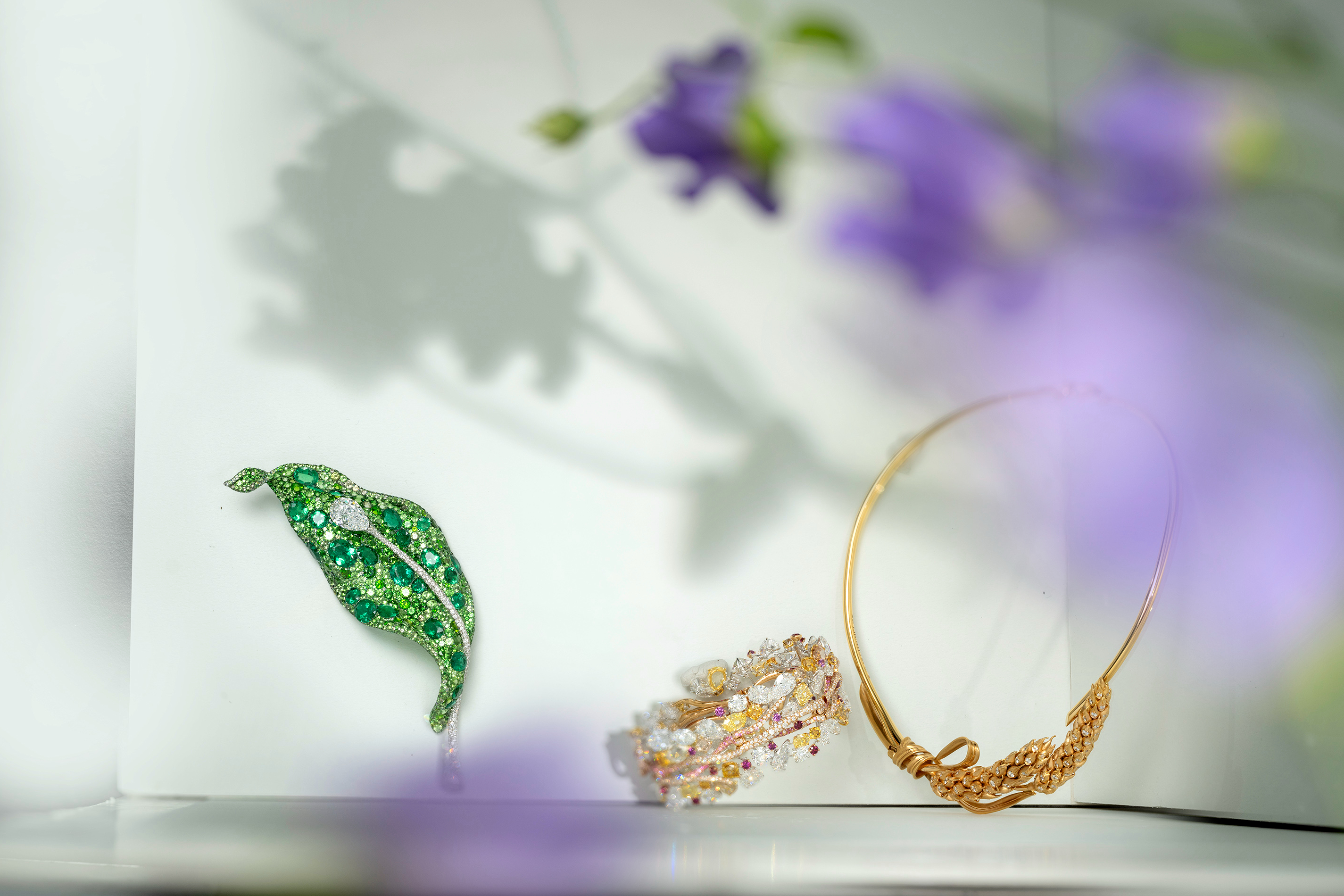 (左) CINDY CHAO The Art Jewel 二十周年系列叶片胸针，18K 白金、钛金属、祖母绿、钻石、沙弗莱石、翠榴石、灰绿蓝宝石。 （中）CINDY CHAO The Art Jewel 四季系列树枝手环，18K 白金、18K 黄金、18K 玫瑰金、白钻、 黄钻、橘黄赞、棕钻、粉色蓝宝石、玫瑰石榴石。 (右) Chaumet L'Épi de Blé de Chaumet 麦穗项链，18K 黄金、钻石。
