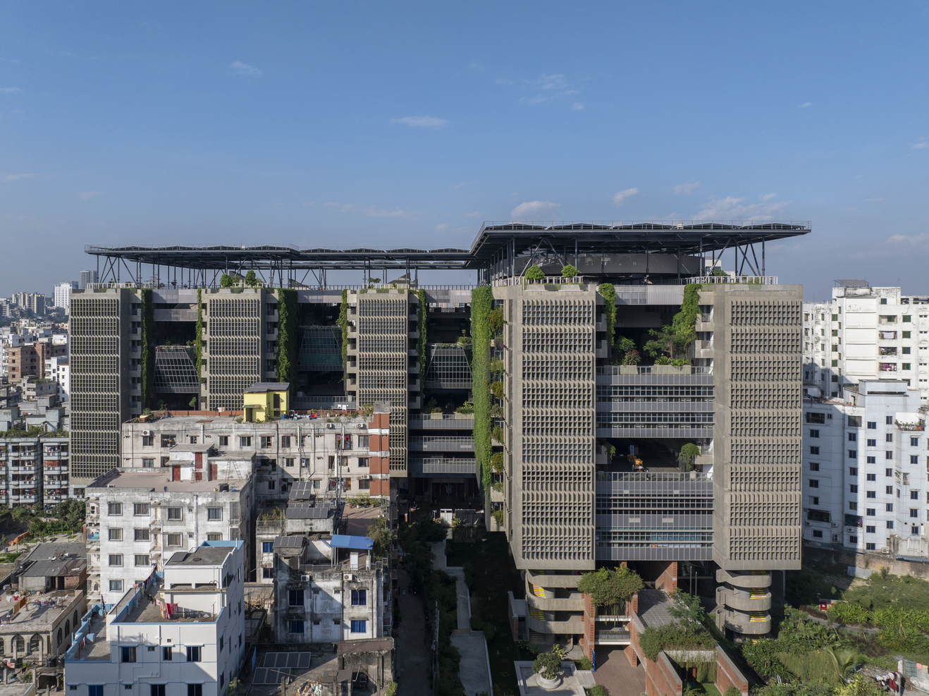 穿孔立面与绿植墙促进交叉通风与遮阳降温。