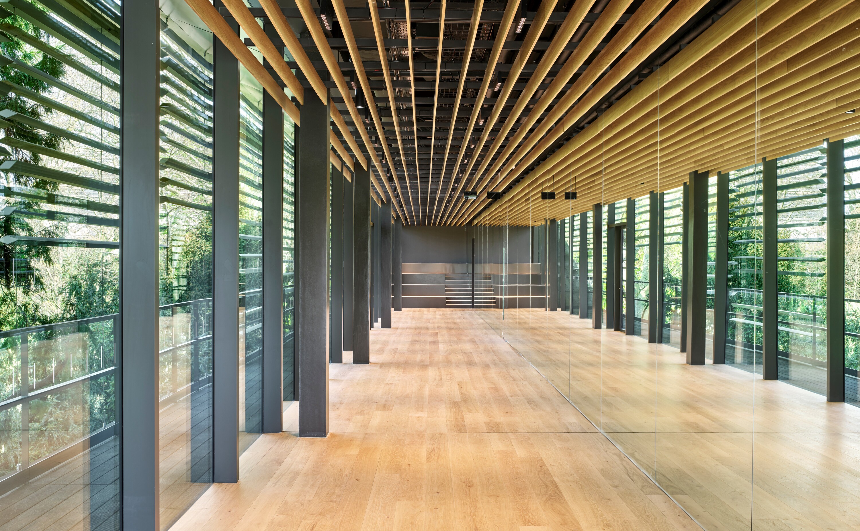 被花園景觀包圍的長廊空間，以水平原木格柵和垂直鋼骨結構，營造出充滿序列感的空間氛圍。 (Photo by Michel Denance)