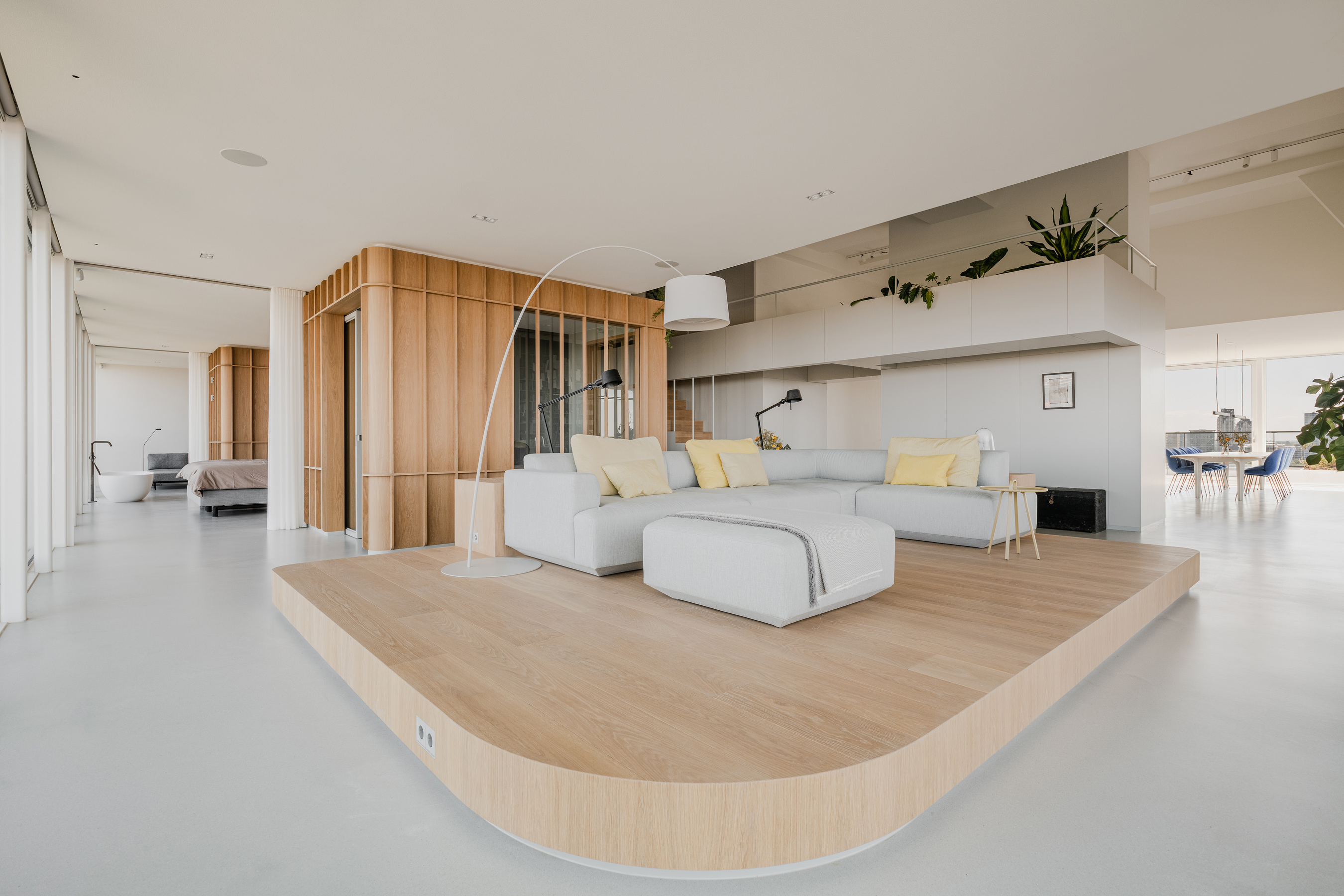 以木地板架高方式定义出起居空间，同时保有开阔视感，简单俐落的 L 型沙发造就无与伦比的首席视野座位区。