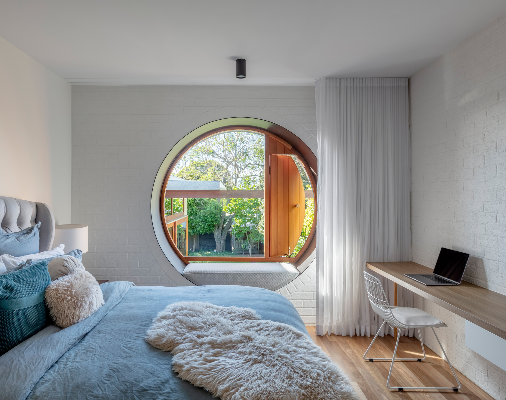 主臥室圓形窗框設計，形塑一方愜意天地，盡覽後院迷人的自然風光。