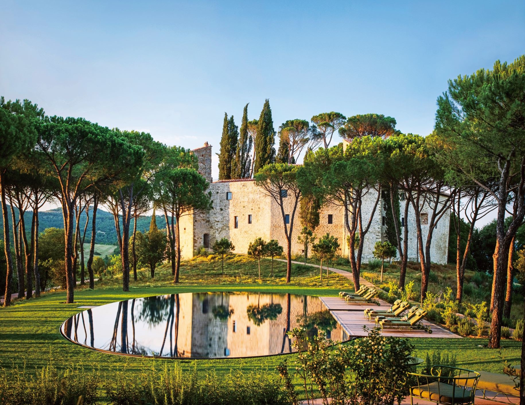 鑲在草坪上的露天泳池像一大面水鏡，映照著 Castello di Reschio 的永恆與美好。